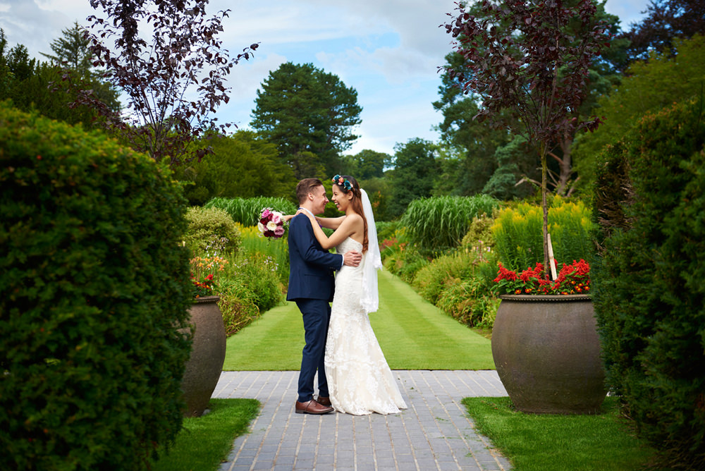 bride and groom hugging intimately in beautiful gardens