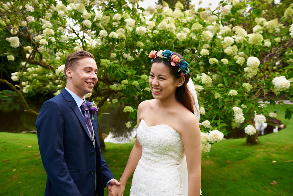 bride and groom laughing in front of blossom tree