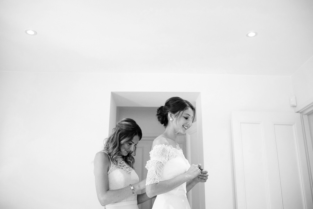 sister helping bride into dress black and white
