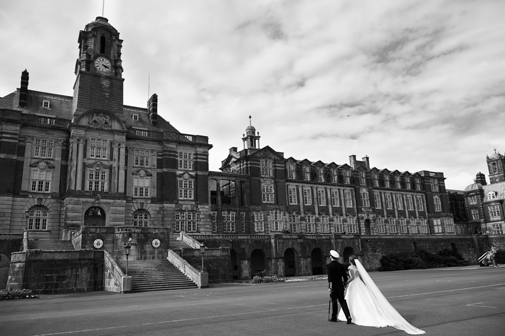 bride and groom walking back towards BRNC in black and white