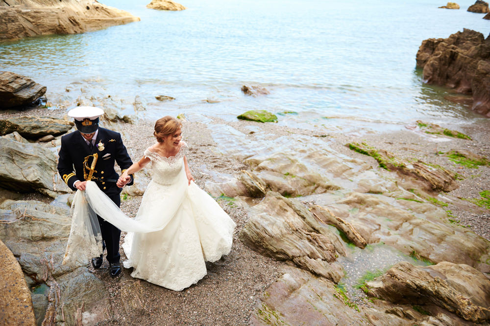 groom helping bride off beach