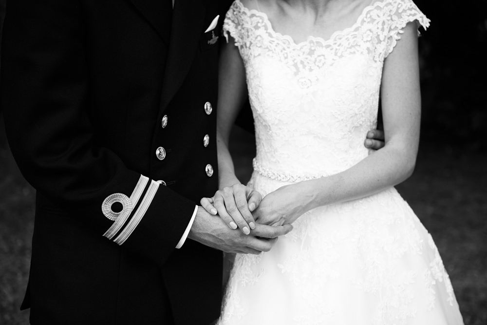 close up of hands of navy groom and uniform and bride