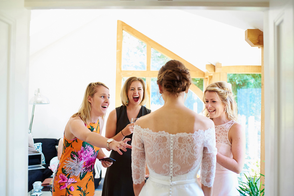 friends seeing bride in her dress for first time and sheer excitment