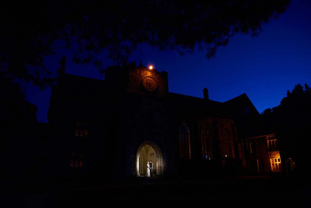 night time portrait of dartington hall with couple in doorway