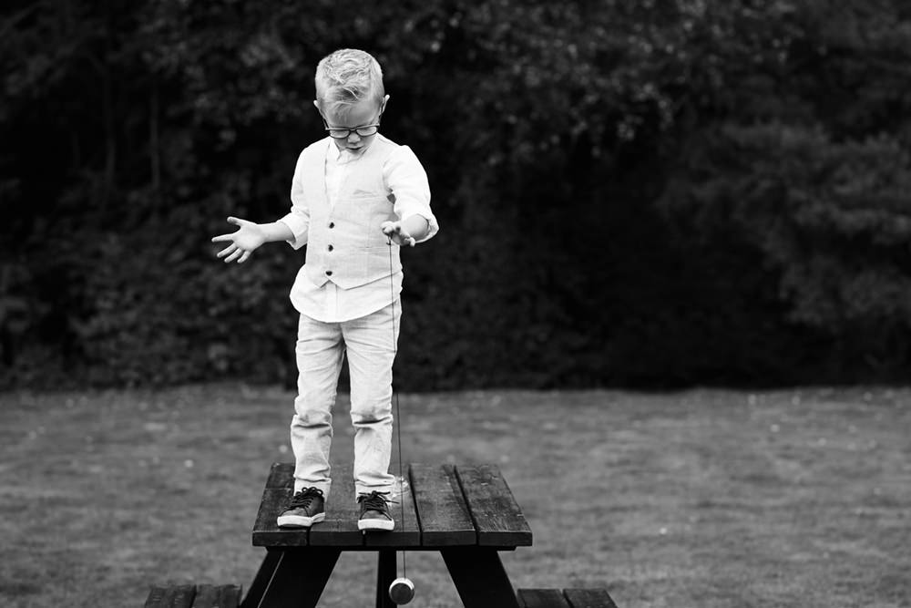 boy playing with yoyo whilst standing on picnic table