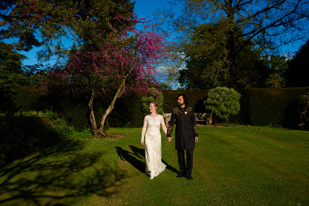 bride and groom walking in beautiful gardens at dartington hall