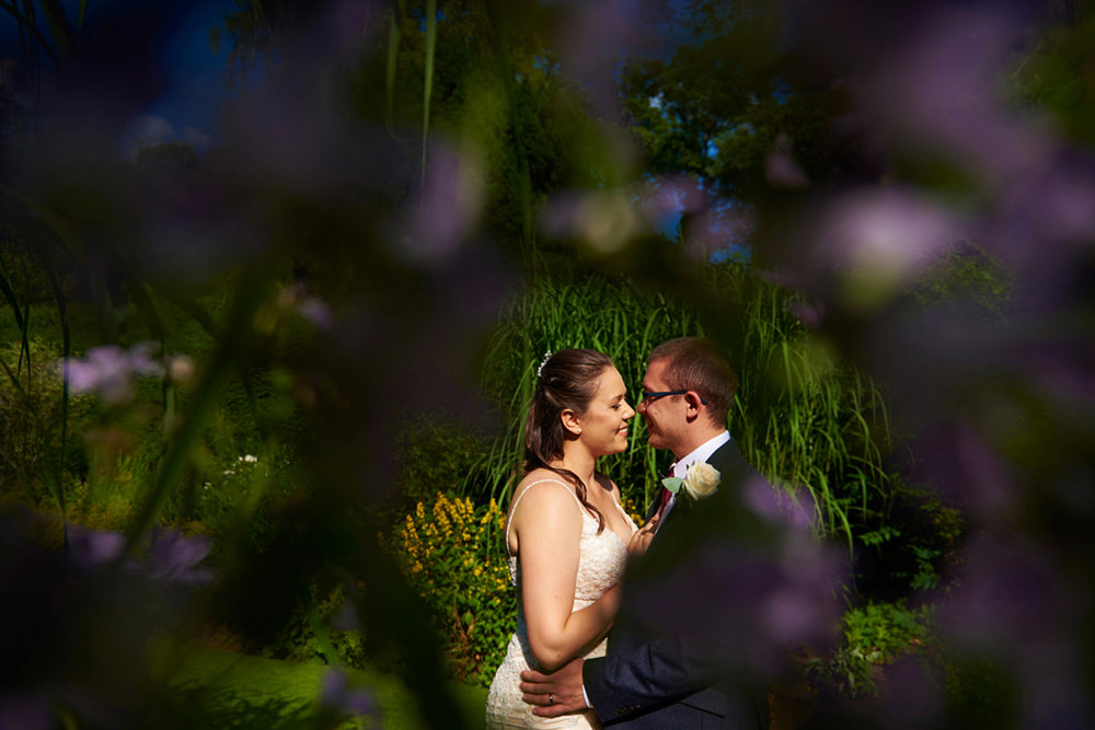 creative portrait through purple flowers of bride and groom