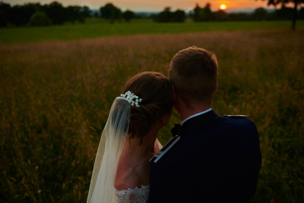 sun just dropping over the horizon with bride and groom watching on