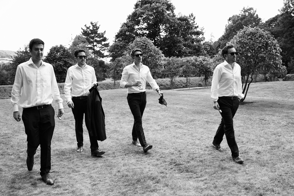 groom and groomsmen walking in black and white