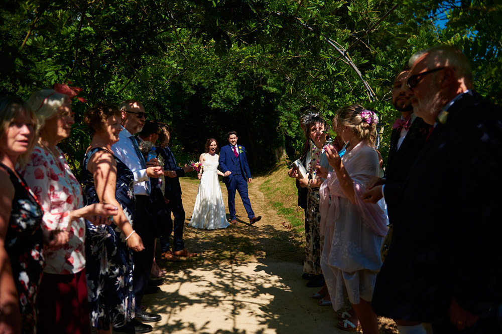 bride and groom about to walk through wisteria tunnel and confetti